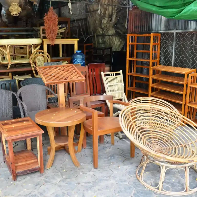 2 1 | Will Move Removalist Wooden furniture assortment in an outdoor shop: chairs, tables, shelves, and a wicker chair in the foreground.