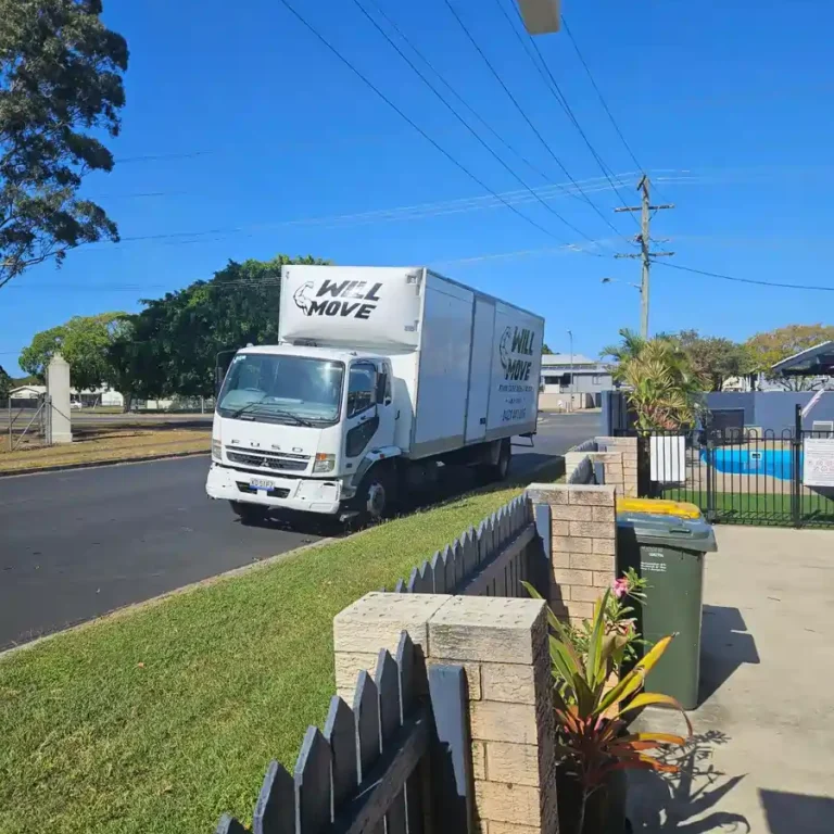 WhatsApp-Image-2024-09-22-at-055803_4b744f8e | Will Move Removalist White moving truck labeled 'WILL MOVE' parked on a suburban street beside a grassy curb and fence.
